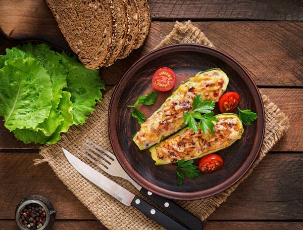 courgettes farcies au poulet, aux tomates et à l'oignon avec une croûte de fromage