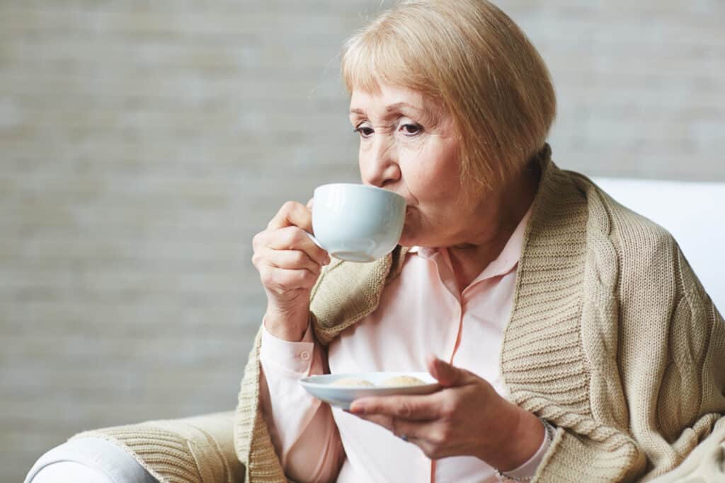 grand-mère boit une tasse de café